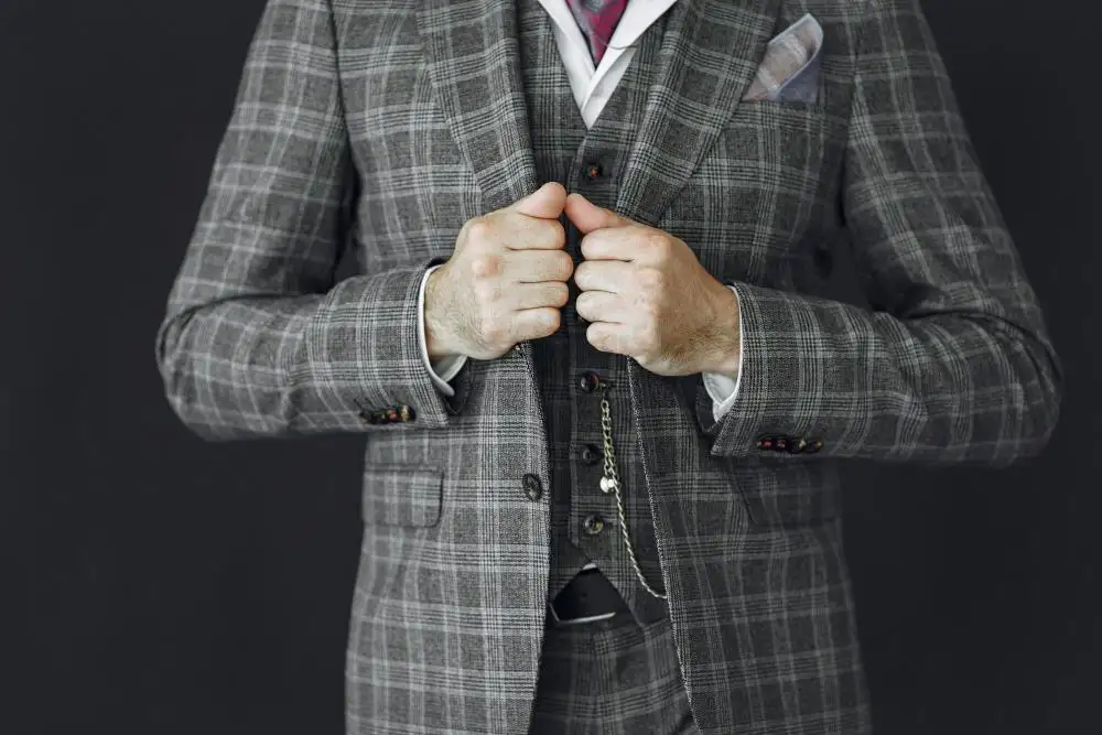 Man in a grey plaid three-piece suit with pocket watch.