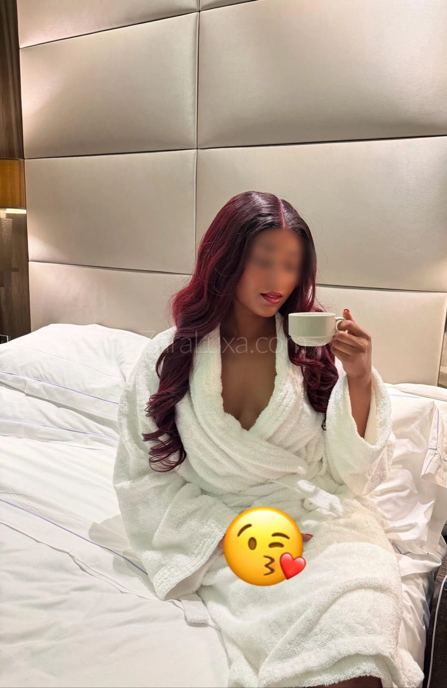 Woman with red hair in white bathrobe holding a cup