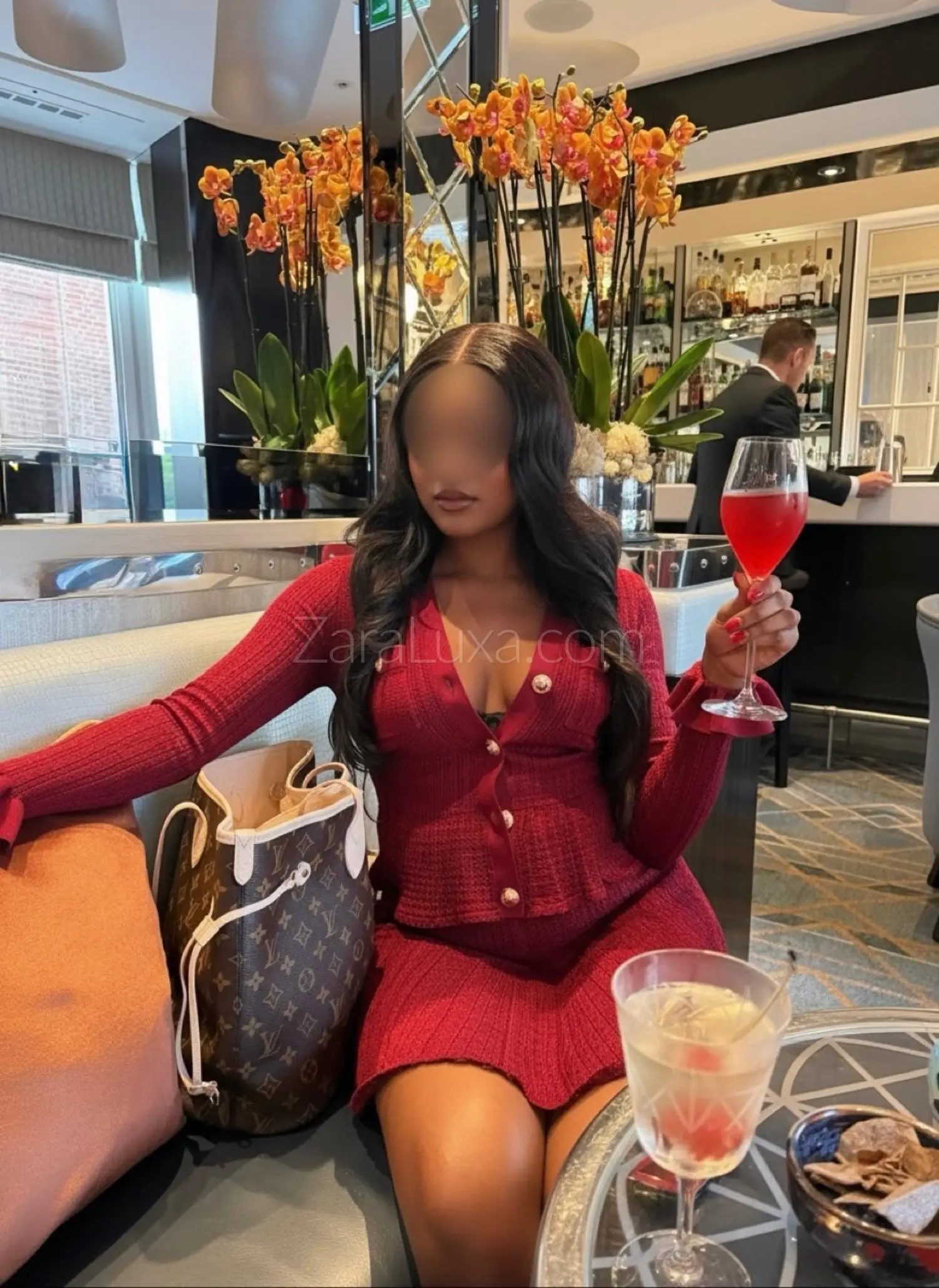 Woman in a red knitted outfit holding a cocktail glass.